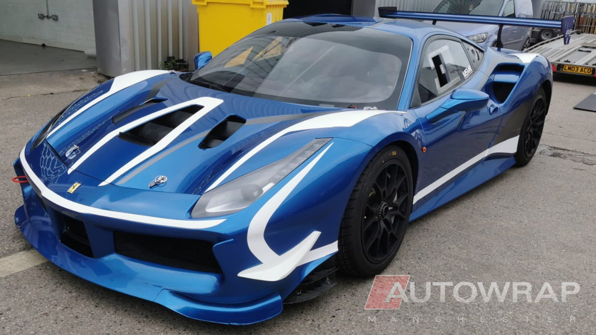 A ferrari challenge car wrap a full exterior wrap and a stripe kit in black and white over the top.